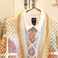 a crocheted jacket and tie hanging on a wall