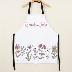 an apron with flowers and the words grandma june on it hanging from a wooden hanger