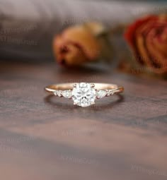 a diamond ring sitting on top of a wooden table next to rose buds and roses