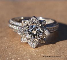 an engagement ring with a flower design on the side and two wedding bands around it