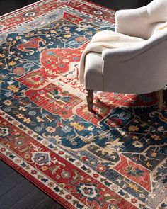 a white chair sitting on top of a red and blue rug next to a window