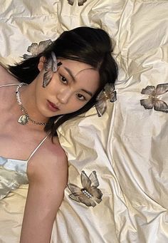 a woman laying on top of a bed covered in white sheets and butterfly hair clips