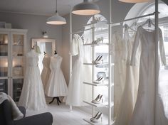 a room filled with lots of white dresses and gowns on display in front of windows