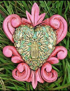 a heart shaped decoration sitting on top of some green grass with pink flowers and leaves