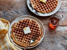 two waffles on plates with butter and syrup next to each other, ready to be eaten