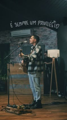 a man standing in front of a microphone while holding a guitar and singing into a microphone