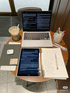 an open laptop computer sitting on top of a wooden table next to a notebook and pen