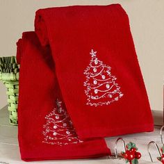 a red towel with a christmas tree embroidered on it next to other holiday decor items