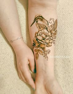 a woman's arm with a bird and flowers tattoo on it