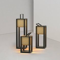 three lamps are sitting next to each other on the floor in front of a white wall