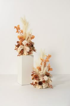 two white vases filled with flowers and feathers