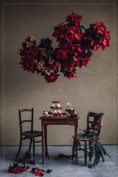 two chairs and a table with desserts on it in front of a wall hanging from the ceiling