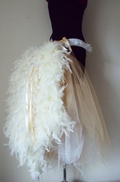 a mannequin with white feathers on it's head and ribbon around the waist