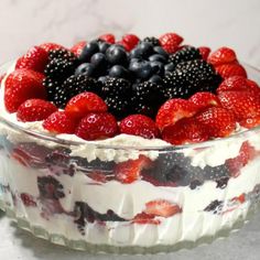 a trifle with berries and blueberries in a glass dish on a counter top