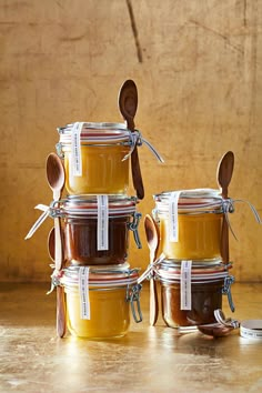 four jars with spoons are stacked on top of each other and one is filled with honey