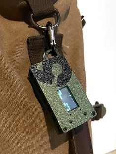 an electronic device is attached to a brown bag with a keychain on it