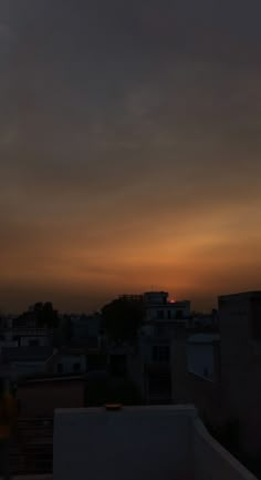 the sun is setting over some buildings and rooftops