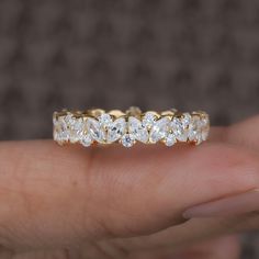 a woman's hand holding a yellow gold ring with five diamonds on it,