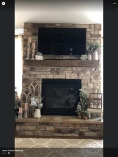 a fireplace with a flat screen tv above it and potted plants on the mantle