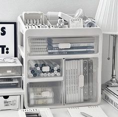 a white desk topped with lots of books and office supplies on top of a table