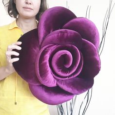 a woman holding a large purple flower in her hands