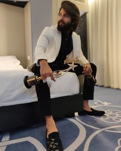 a man sitting on top of a bed in a bedroom next to a blue carpet