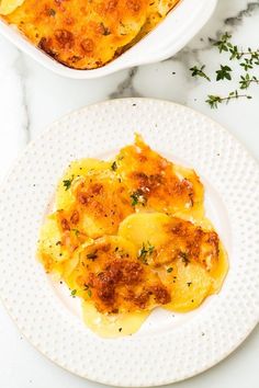 two white plates topped with food on top of a marble countertop next to a bowl of macaroni and cheese