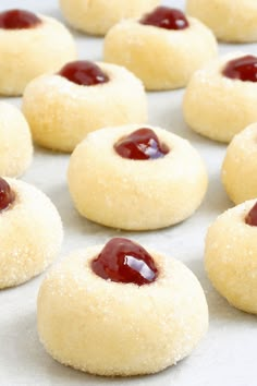 small cookies with jam on them sitting on a baking sheet, ready to be baked