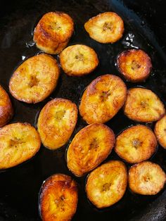 fried bananas are being cooked in a black skillet with oil on the stove top