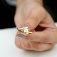 a woman's hand holding a gold ring with two small diamonds on the middle