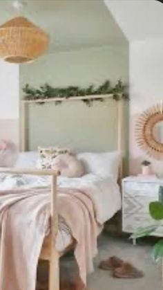 a bedroom decorated in pink and white with plants on the bed, pillows and blankets