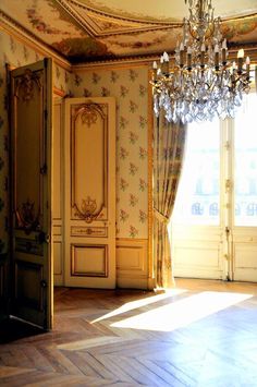 an empty room with chandelier and curtains