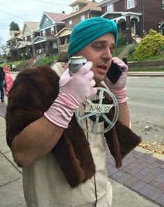 a man in a turban talking on a cell phone while wearing gloves and holding a peace sign