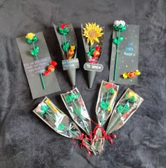 five different types of paper flowers on a bed with some tags attached to the stems