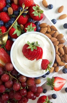 strawberries, grapes, almonds, and yogurt on a white plate