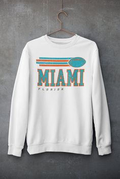 Dolphins Sweatshirt - Vintage Dolphins Sweatshirt - Miami Sweatshirt - Fins Up Sweatshirt - Florida Sweatshirt - Dolphins Football Gift  -- UNISEX -- 💎PRODUCT DETAILS & SIZING ** Gildan 18000, unisex heavy blend crewneck sweatshirt ** Pre-Shrunk 50% Cotton/50% Polyester made with softer air-jet spun yarn ** Size chart can be found on listing photos ** Unisex fit, runs true to size ** Colors may be slighty brighter in the mockups 👕CARE INSTRUCTIONS ** Machine wash cold, inside out, with like colors ** Only non-chlorine bleach ** Tumble dry low/but hang dry works best ** Medium Iron ** Do not iron graphic ** Do not dry clean ⏱️SHIPPING AND PRODUCTION TIME ** Production time is 1-5 business days ** Shipping time is 2-5 business days 👐FEEDBACK ** I would highly appreciate your feedback as a Crew Neck Top With Screen Print Fan Apparel, White Tops For Fan Merchandise In Fall, White Tops For Fall Fan Merchandise, White Crew Neck Top For College, White Long Sleeve Tops For Fan Gear, Fan Apparel Sweater With Letter Print, Crew Neck Text Print Sweatshirt For Team Spirit, White Crew Neck Top With Team Spirit Style, White Sweatshirt For Fall Fan Merchandise