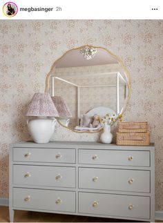 a white dresser topped with a mirror next to a lamp