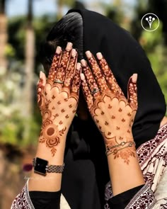 a woman with her hands on her face covered in hendi and bracelets, covering her eyes