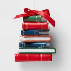 a christmas ornament made out of books with a red ribbon hanging from it