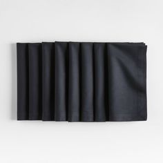 black napkins lined up on top of each other in front of a white wall