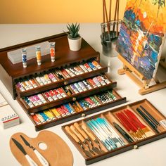 an assortment of art supplies displayed on a table with paintbrushes and palettes