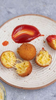 three fried food items on a plate with ketchup and mayonnaise sauce