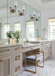 a bathroom with two sinks, mirrors and gold trim on the cabinets in front of them