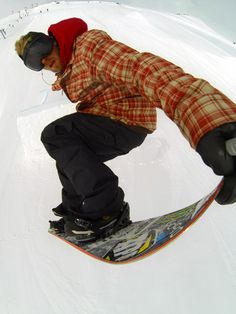 a man riding a snowboard down the side of a snow covered slope