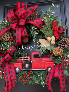 a christmas wreath with a red truck, pine cones and berries on the front door