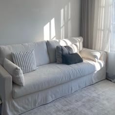 a white couch sitting next to a window in a living room