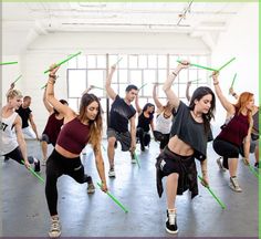 a group of people in a dance class doing different moves with green hula hoops