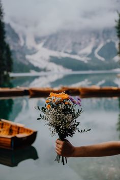 a bouquet of flowers being held in front of a body of water