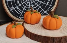 three small pumpkins are sitting on wood slices