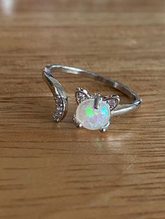 This super cute, silver tone, cat ring is very cute! It's is adjustable and has a small simulate opal in the center and small rhinestones in the tail. It's made of copper. It's a great small accessory to add to any outfit and show your love for your cat!